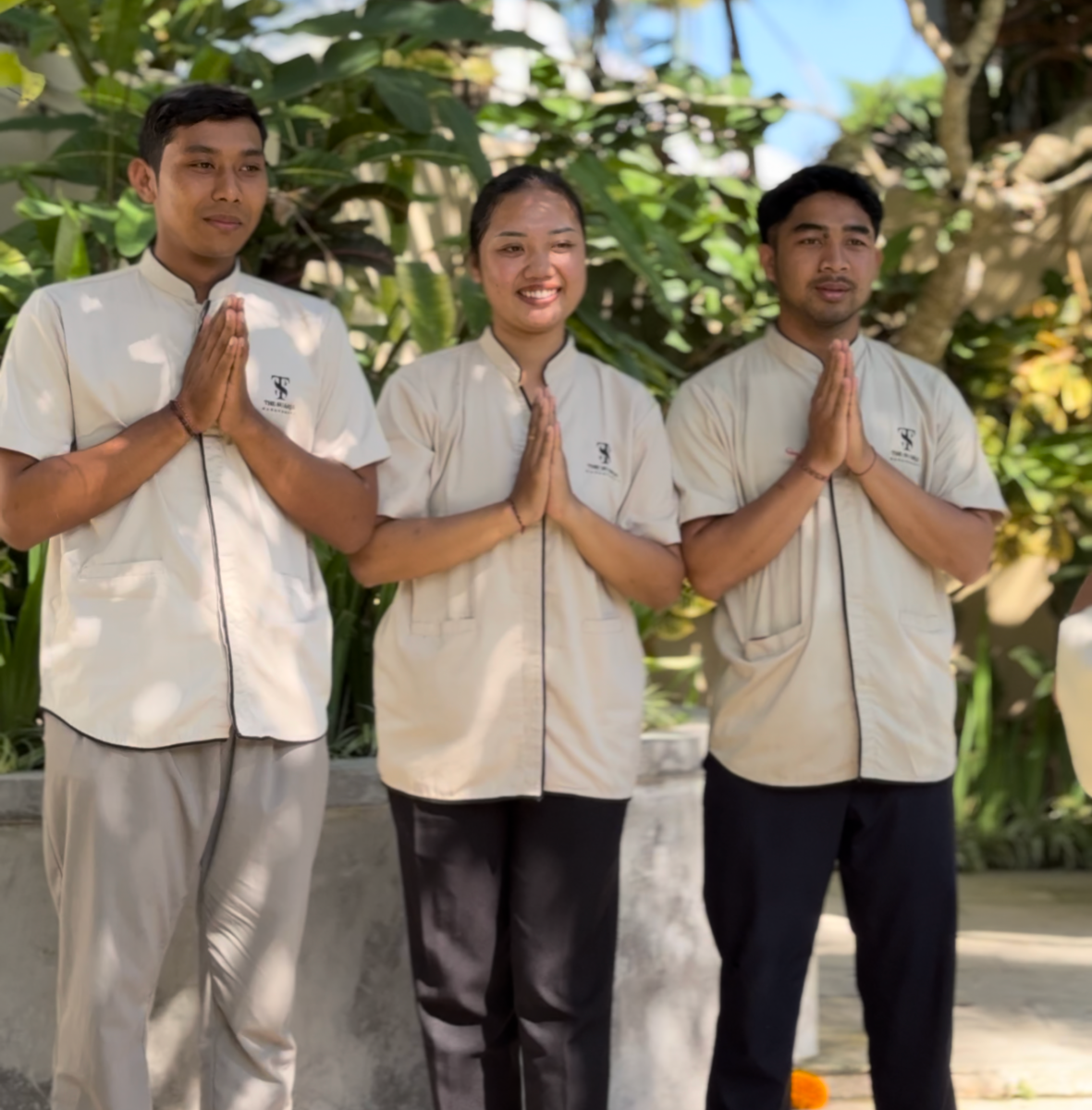Three individuals in prayer pose outdoors.