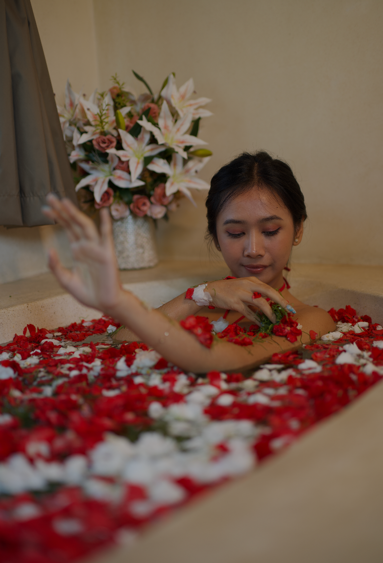 Person relaxing in flower-filled bath.